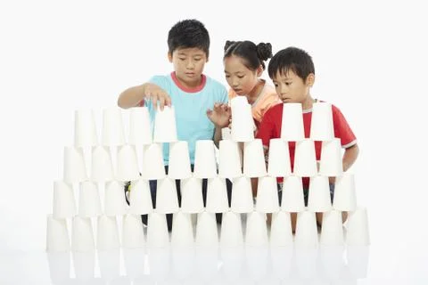 Three children stacking up disposable cups Stock Photos