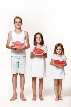 Three children in the studio stand on a white background and hold pieces of w Stock Photos