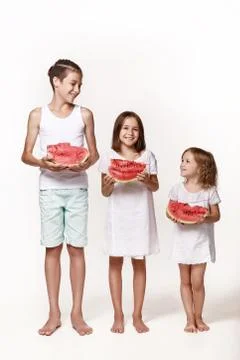 Three children in the studio stand on a white background and hold pieces of w Stock Photos