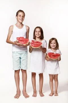 Three children in the studio stand on a white background and hold pieces of w Stock Photos