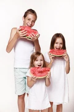 Three children in the studio stand on a white background and eat pieces of wa Foto stock