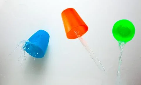 Three children's multicolored plastic cups with splashes Stock Photos