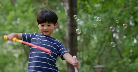 Three Chinese children blowing bubbles on grass,4K Stock Footage 119088038