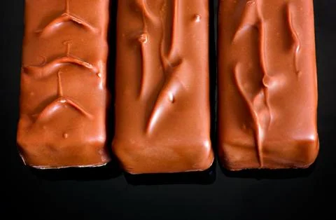 Three chocolate bars in a row. Black background. Stock Photos