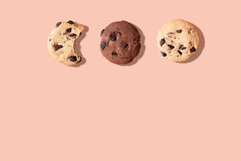 Three chocolate chip cookies, one bitten on a brown background. Foto stock