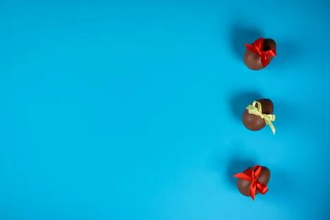Three chocolate eggs on the blue background. Easter concept. Stock Photos