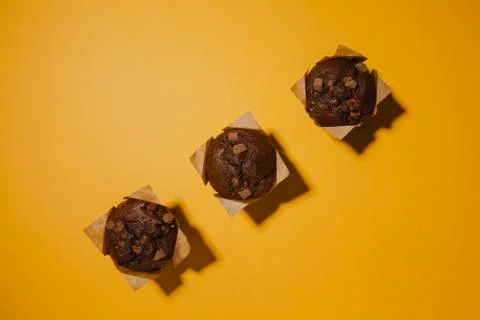 Three chocolate muffins on orange background. Stock Photos
