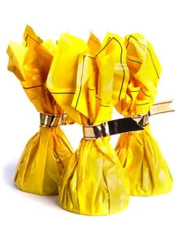 Three chocolates in a yellow wrapping with silver ribbons Foto stock
