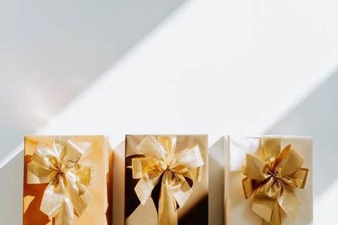 Three Christmas gift boxes, adorned with vibrant golden ribbons on white ba.. Stock Photos