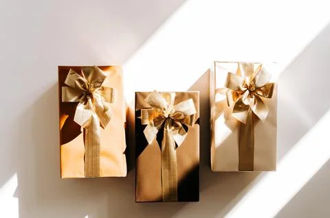 Three Christmas gift boxes, adorned with vibrant golden ribbons on white back Stock Photos