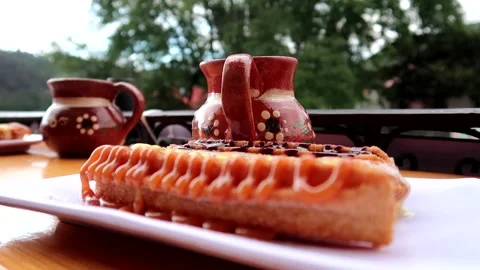 Three churros in front on a plate with coffee Stock Footage 287498126