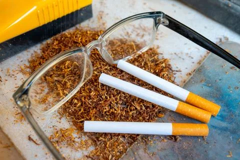 Three cigarettes resting on a pile of loose tobacco leaves with clear readi.. Stock Photos