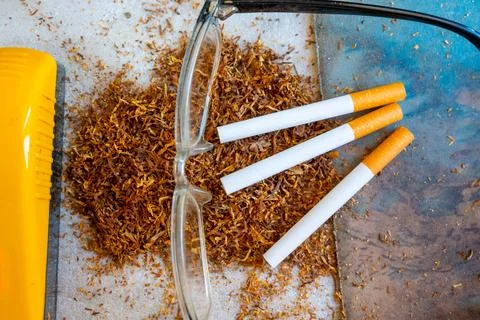 Three cigarettes resting on a pile of loose tobacco leaves with clear readi.. Stock Photos