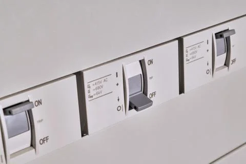 Three circuit breakers are arranged in a row in an electrical Cabinet. Stock Photos
