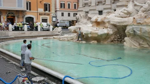 Three city workers clean coins from Trevi Fountain and people watch - Wide, 4K Stock Footage 155748611