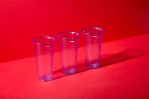 Three Clear Plastic Cups on Red Background with Copy Space Stock Photos