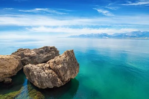 Three cliffs in sea with crystal clear water, blue sky and mountains on horiz 写真素材