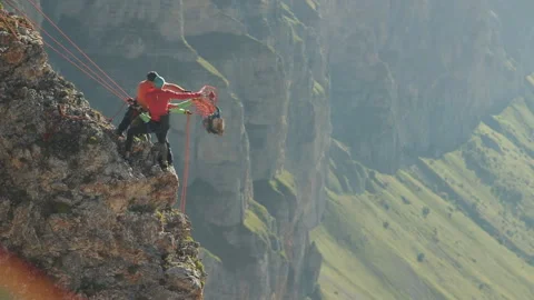 Three climbers take off the load from the rock on a rope. 動画素材 97766090