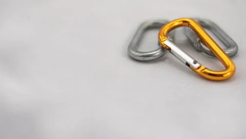 Three climbing carabiners, two gray and one orange on white background Stock Photos