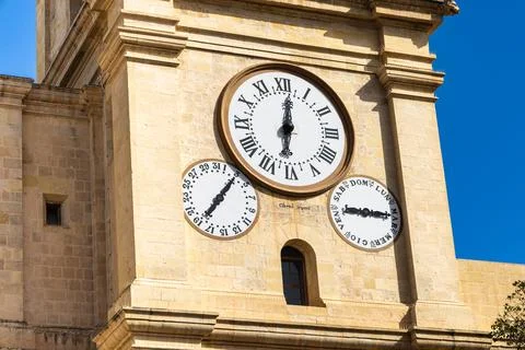 Three clock faces on the limestone tower showing the time, day of the week,.. Stock Photos
