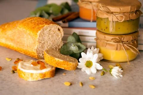 Three closed jars with fruit jam and  cuted bread with raisins are on the table Stock Photos