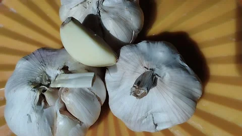 Three cloves of garlic placed in an orange place Stock Footage 221748490