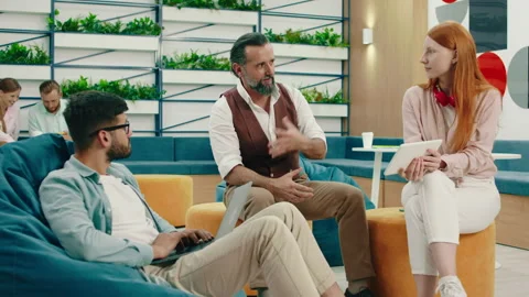 Three co-workers are having a friendly conversation about work and are sitting Stock Footage 166911795