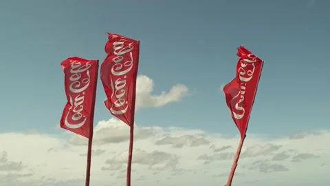 Three coca cola flags flutters with a blue and cloudy sky Video stock 135515761