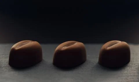 Three coffee bean shape chocolate on dark background Stock Photos