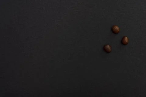 Three coffee beans on a black background, minimalistic design. Stock Photos