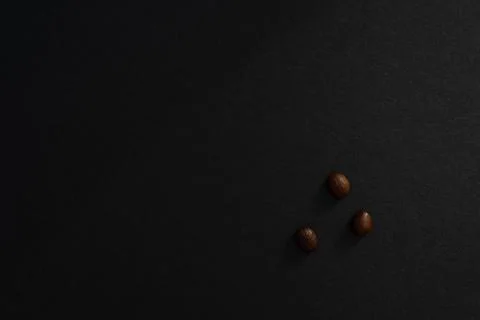 Three coffee beans on a black background, minimalistic design. Stockfoto's