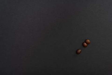 Three coffee beans on a black background, minimalistic design. Stock Photos