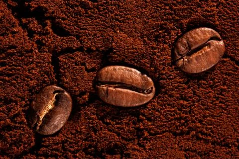 Three coffee beans on ground coffee close up Foto stock