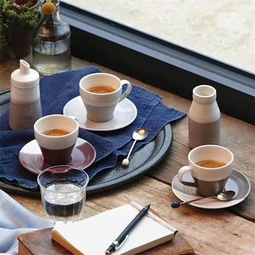 Three coffee cups, notebook and water glass on wooden table in coffee house i Stock Photos