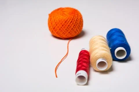 Three coils of multi-colored thread and a hank of orange Stock Photos