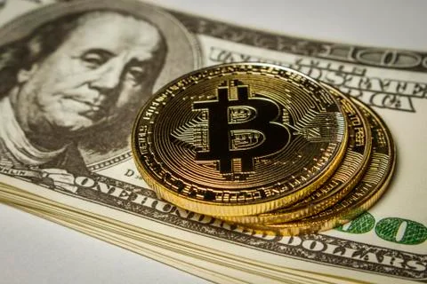 Three coins of bitcoin on a pack of dollars on a table Stock Photos