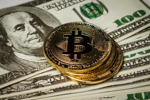 Three coins of bitcoin on a pack of dollars on a table Stock Photos