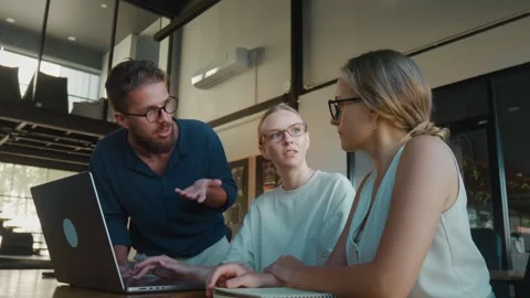 Three colleagues brainstorming discussing a project, collaborating around laptop Stock Footage 312117967
