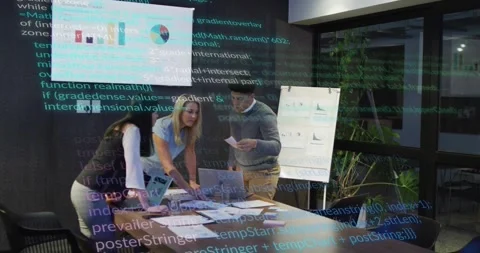 Three colleagues leaning in, pointing at laptop and charts, code overlay framing Stock Footage 328396090