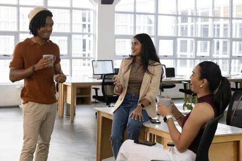 Three colleagues sharing coffee, man raising mug starting casual chat in flat Stock Photos