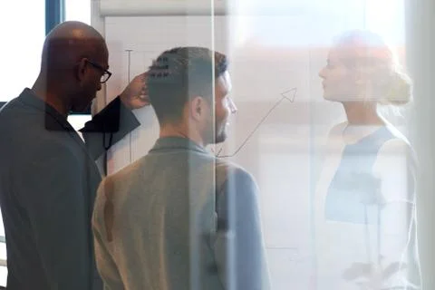 Three colleagues standing looking at a chart Stock Photos