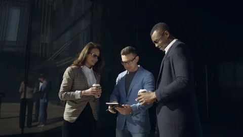 Three colleagues in sutes during lunch time, watching news on tablet, front of Stock Footage 107152136