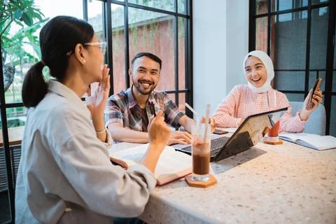 Three college students chatting using cellphones and a laptop Stock Photos