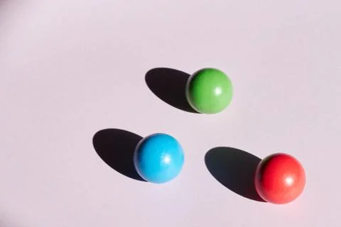 Three colored balls on a light background with hard shadows. abstract backgro Stock Photos