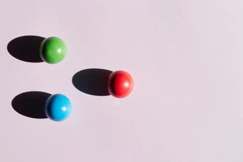 Three colored balls on a light background with hard shadows. abstract backgro Stock Photos