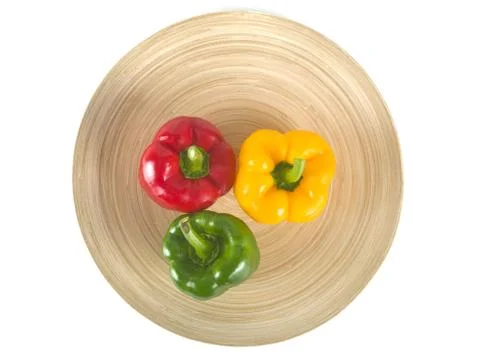 Three colored bell pepper on a wooden plate Stock Photos