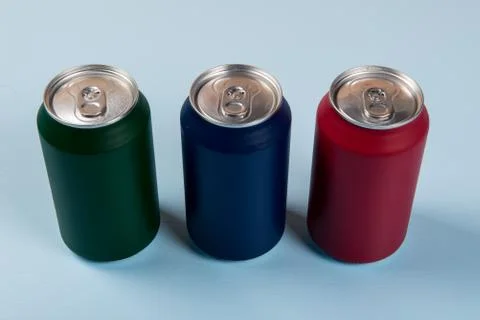 Three colored cans of soft drinks closed on a light blue background Stock-Fotos