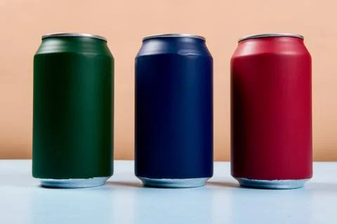 Three colored cans of soft drinks closed on a light blue background Foto stock