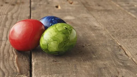 Three colored Easter eggs on a rustic wooden table, Happy Easter background Stockfoto's