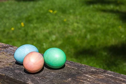 Three colored easter eggs sitting on a railing Stock Photos